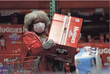  ?? JUSTIN SULLIVAN/GETTY IMAGES ?? A customer picks up a box of Huggies diapers at a Costco store in Novato, California.