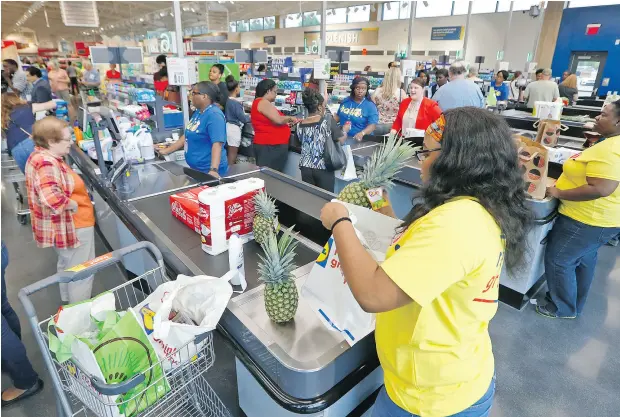  ?? STEVE HELBER / THE ASSOCIATED PRESS ?? Shoppers get their groceries bagged during the grand opening of a Lidl grocery store in Virginia Beach, Va., last week. Several Lidl stores opened across the U. S. last week as the German chain tries to win over American consumers with curated wines,...