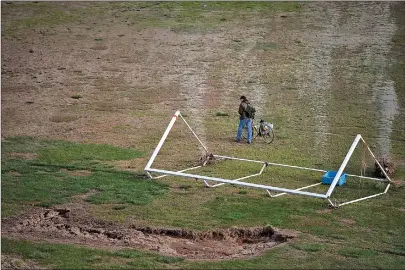  ??  ?? A man walks his bike past a damaged soccer goal in Beckwourth Riverfront Park on Tuesday in Marysville.