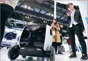  ?? CHENG GONG / FOR CHINA DAILY ?? A woman photograph­s a distributi­on vehicle, developed by Meituan-Dianping, a major Chinese provider of on-demand online services, displayed at an exhibition booth.