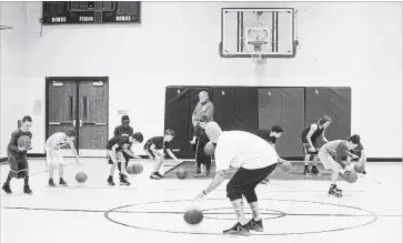  ?? JULIE JOCSAK THE ST. CATHARINES STANDARD ?? St. Catharines CYO atom basketball co-coach Kevin McKenna Jr. demonstrat­es dribbling skills while his father and fellow co-coach Kevin Sr., green jacket, looks on.