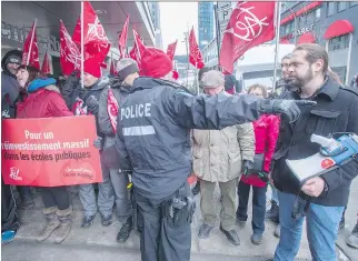  ?? RYA N R E MI O R Z / T H E C A NA D I A N P R E S S ?? Police keep an eye on anti- austerity protesters outside the hotel where Premier Philippe Couillard addressed the Chamber of Commerce Friday in Montreal.