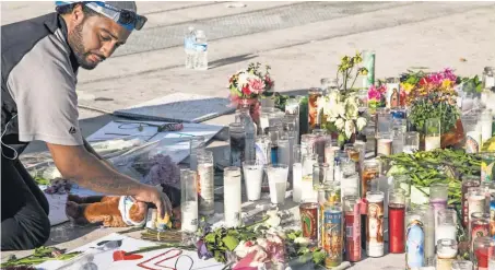  ?? NICK OZA, USA TODAY NETWORK ?? Matthew Edwards, 30, of San Diego places a teddy bear and flowers at amemorial site on the corner of Las Vegas Boulevard and Sahara Avenue.