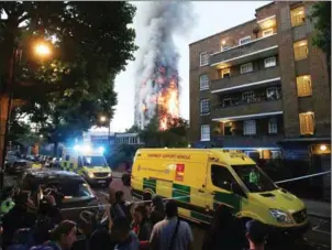  ?? DANIEL LEAL-OLIVAS/AFP ?? A security cordon holds people back as Grenfell Tower is engulfed by fire on Wednesday in west London.
