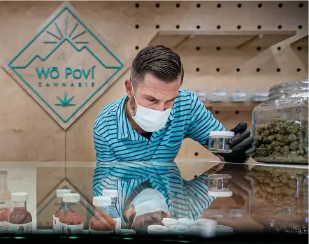  ?? JIM WEBER/THE NEW MEXICAN ?? Wõ Poví Cannabis manager Drew Little stocks a display case Tuesday at the new dispensary on Pojoaque Pueblo.