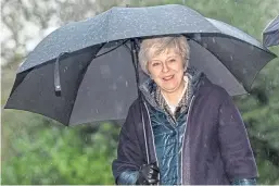  ?? Picture: PA. ?? Under a cloud: Theresa May shelters from the rain as she plots the UK’s departure from the EU.