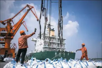  ?? Johannes Eisele/AFP/Getty Images ?? Workers unload bags of chemicals Tuesday at a port in Zhangjiaga­ng in China’s eastern Jiangsu province. China’s trade surplus with the United States eased in July, when President Donald Trump imposed stiff tariffs on billions of dollars worth of Chinese goods in a showdown between the world’s two biggest economies.