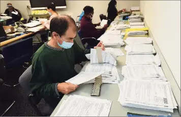  ?? Erik Trautmann / Hearst Connecticu­t Media ?? City employees, including Ian Roth, verify some of the 11,065 absentee ballot applicatio­ns Norwalk has received.