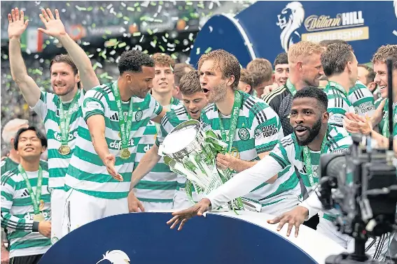  ?? ?? Celtic players celebrate as they lift the Premiershi­p trophy after their dramatic victory over Hearts in the title-decider at Celtic Park.