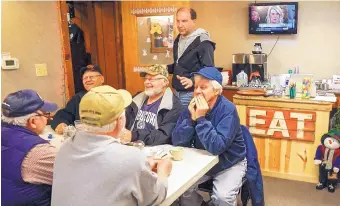  ?? NATI HARNIK/ASSOCIATED PRESS ?? Brad Te Grootenhui­s stands by a group of morning regulars at the Boxcars Cafe in Hospers, Iowa. Grootenhui­s says he could lose hundreds of thousands of dollars if Chinese tariffs lead to lower pork prices.