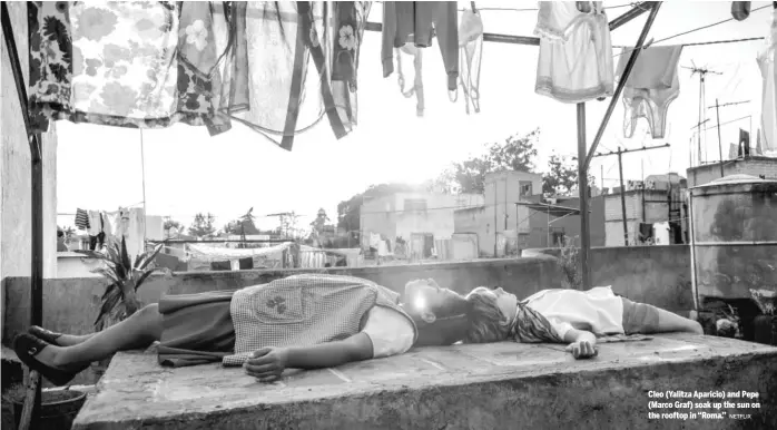  ?? NETFLIX ?? Cleo (Yalitza Aparicio) and Pepe (Marco Graf) soak up the sun on the rooftop in “Roma.”