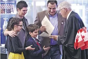  ?? ED KAISER ?? Cal Nichols hands out citizenshi­p certificat­es to the Bubevski family, Zoran (dad), Renata (mom), Veda, 10, and Davian, 7, all from Macedonia, at Rogers Place on Saturday.