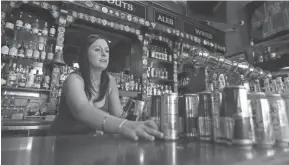  ?? RICH PEDRONCELL­I/AP FILE ?? Courtney Schrag arranges beverage cans while preparing to close de Vere’s Irish Pub in Sacramento, Calif. Local officials and businesses ascross the region were confused by permission to reopen because state officials won’t share their data.