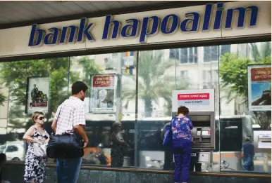  ?? (Nir Elias/Reuters) ?? A BANK HAPOALIM branch in Tel Aviv. NIS 60m. has been put away to cover a possible future settlement in the US investigat­ion.