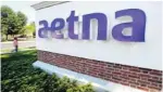  ??  ?? A pedestrian walks past a sign for Aetna Inc., at the company headquarte­rs in Hartford, Conn.