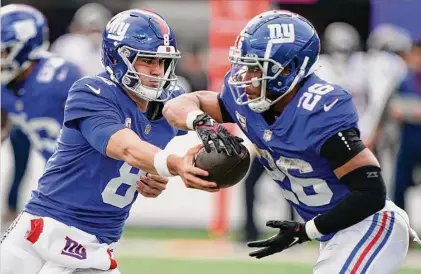  ?? John Minchillo/Associated Press ?? New York Giants quarterbac­k Daniel Jones (8) hands off the ball to New York Giants running back Saquon Barkley (26) during the second quarter on Nov. 13 in East Rutherford, N.J. The Giants put the franchise tag on Barkley.