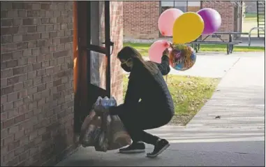  ??  ?? Erica Stowe delivers groceries and balloons to a student in Ann Arbor, Mich.