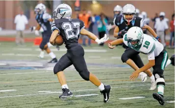  ??  ?? Capital’s Daniel Roybal, left, eludes Pojoaque’s Bryan Martinez during the first quarter. The Jaguars rolled to a win in the season opener.