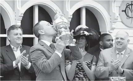  ?? KIM HAIRSTON/BALTIMORE SUN ?? Cloud Computing’s trainer Chad Brown kisses the Woodlawn Vase in the winners circle. Cloud Computing, owned by former Baltimore resident Seth Klarman and ridden by Javier Castellano, won the 142nd Preakness Stakes.