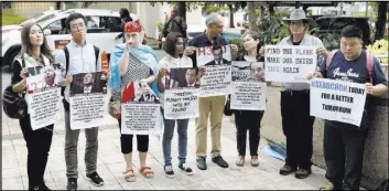  ?? VINCENT THIAN/THE ASSOCIATED PRESS ?? Family members of passengers on board the Malaysia Airlines Flight 370 that went missing on March 8, 2014, hold up signs after a joint news conference by Malaysia, China and Australia on Friday in Putrajaya, Malaysia. The countries have agreed to...