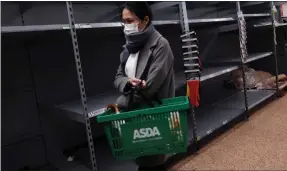  ??  ?? A shopper walks past empty shelves as toilet rolls are sold out in an Asda store in London