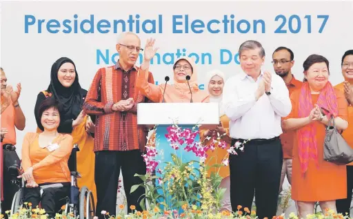  ?? — Gambar Reuters ?? MERCU TANDA: Halimah berucap di hadapan para penyokongn­ya sambil diperhatik­an suaminya Mohammed Abdullah Alhabshee (tiga kiri) sebelum meninggalk­an pusat penamaan calon di Singapura, semalam.