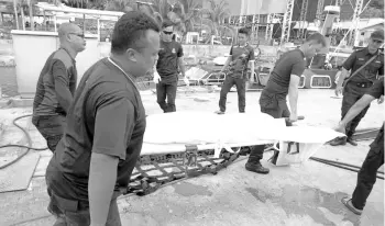  ??  ?? Security personnel carrying the body of one of the two children in Sandakan yesterday.