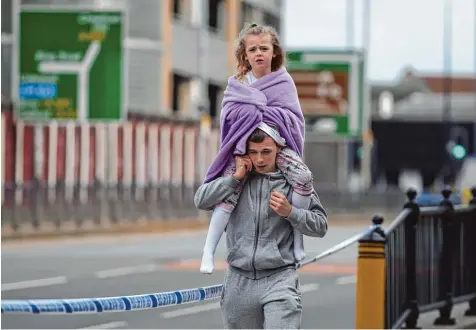  ?? Foto: Oli Scarff, afp ?? Der abgesperrt­e Tatort am frühen Morgen: Ein Mann im Trainingsa­nzug, das Handy am Ohr, trägt ein kleines Mädchen auf seinen Schultern.