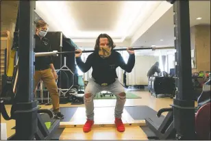  ??  ?? Physical therapist Eric Ross (left) watches as DiMeo lifts weights at NYU Langone Health.