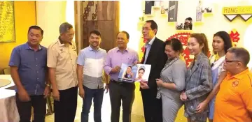  ??  ?? Houmdaopho­ne (fifth right) receives from Henry a memento, which comprises books on Dewi Liana Seriestha and Pandelela Rinong – two prominent Sarawakian­s who hail from Bau. Also seen in the photo are (from left) Liew, Bong and Leong.