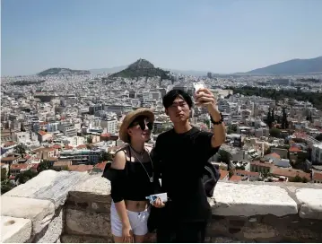  ?? (Costas Baltas/Reuters) ?? TOURISTS TAKE a selfie as they visit the Acropolis hill in Athens, Greece.