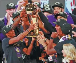  ?? KIM KLEMENT / REUTERS ?? Los Angeles Lakers team members (above left) celebrate on Sunday after the Lakers defeated the Miami Heat 106-93 in basketball’s NBA Finals in Lake Buena Vista, Florida. Rafael Nadal of Spain (above right) hoists his trophy during the award ceremony after winning the men’s singles final match against Novak Djokovic of Serbia at the French Open tennis tournament at Roland-Garros in Paris on Sunday.