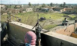  ?? FELIPE DANA/AP ?? A U.S.-backed SDF fighter stands atop a building used as a temporary base near the last land still held by Islamic State militants in Baghouz, Syria, on Monday.