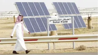  ??  ?? A Saudi man walks on a street past a field of solar panels at the King Abdulaziz City of Sciences and Technology (KACST), Al-Oyeynah Research Station in this file photo. (Reuters)