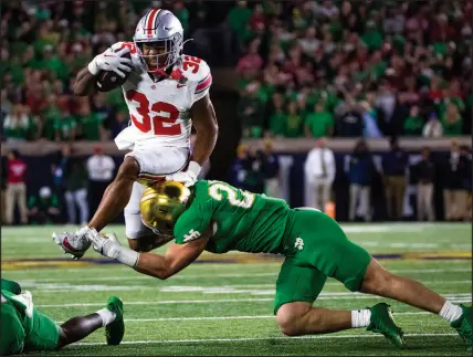  ?? MICHAEL CATERINA / ASSOCIATED PRESS ?? Ohio State running back Treveyon Henderson (32) tries to jump over Notre Dame linebacker JD Bertrand during the Buckeyes’ 17-14 victory Sept. 23 in South Bend, Ind. Ohio State’s defense has given up an average of 9.7 points per game this season, but on Saturday faces a Penn State team that’s scored at least 30 points in all six of its contests.