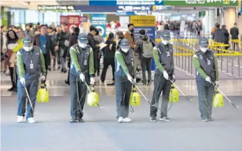  ?? FOTO: STR / YONHAP / AFP ?? Am Flughafen von Incheon westlich der südkoreani­schen Hauptstadt Seoul treffen Arbeiter mit Desinfekti­onsspray Maßnahmen, um Reisende vor dem Coronaviru­s zu schützen.