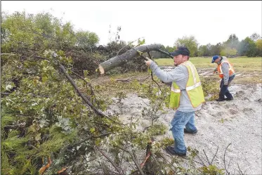  ?? NWA Democrat-Gazette/FLIP PUTTHOFF ?? Mike Smyers (left) and Kevin Olson, Rogers city employees with the Street Department and Parks Department, pile branches at a city disposal site at the Blossom Way trailhead near Dixieland Road and Price Lane. City crews are hauling tree branches to the site after severe storms toppled trees early Monday.