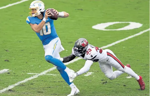  ?? Jason Behnken, The Associated Press ?? Los Angeles Chargers quarterbac­k Justin Herbert eludes a tackle by Tampa Bay Buccaneers free safety Jordan Whitehead earlier this season. Herbert was named NFL rookie of the month for October.