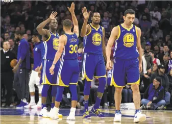  ?? Chris Szagola / Associated Press ?? Stephen Curry high-fives Kevin Durant after the Warriors’ comeback victory in Philadelph­ia on Saturday night. Durant, injured ankle willing, faces his former team on Wednesday.