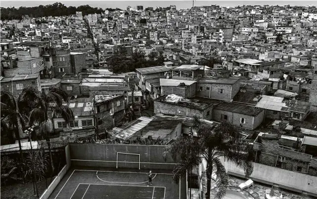  ?? Lalo de Almeida/Folhapress ?? Mulher joga tênis em quadra de prédio de alto padrão no bairro do Morumbi, zona sul de São Paulo, com a vizinha favela de Paraisópol­is ao fundo