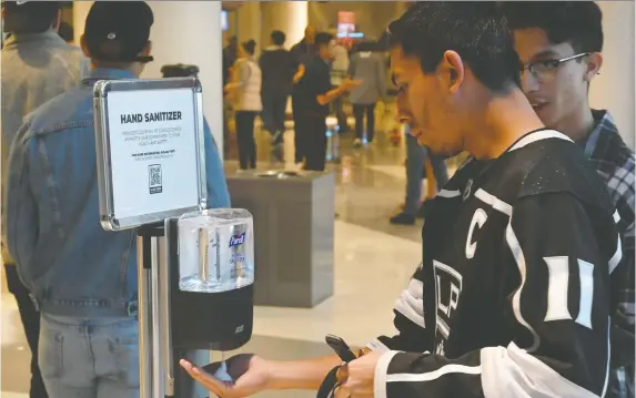  ?? KIRBY LEE/USA TODAY SPORTS ?? The Senators’ last game was March 11 in Los Angeles against the Kings. Here fans use a hand sanitizer station at the Staples Center before the game began.