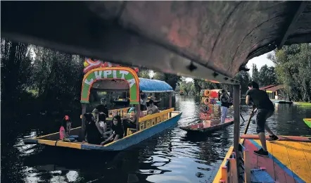  ?? REBECCA BLACKWELL/ASSOCIATED PRESS ?? A flower crown vendor plies his wares between two trajineras, colorful passenger boats typically rented by tourists, families and groups of young people, in Xochimilco, Mexico City, last week. Some boat operators and vendors estimate business was down 80 percent on the first weekend following the drowning death of a youth that was captured on cellphone video and seen widely in Mexico.