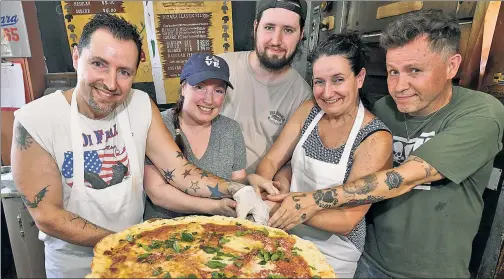  ??  ?? OVEN-FRESH: Di Fara sibling owners (from left) Dominic, Louisa, Harry, Margaret and Michael DeMarco display their first back-in-biz pie Thursday as hero accountant Vinny Cervone scrapes away the state’s “seized” notice.