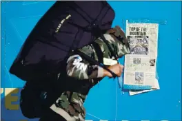  ?? RANDY VAZQUEZ — BAY AREA NEWS GROUP ?? A San Jose State University football player carries a bag past the front page of the Mercury News when the team won the Mountain West Conference before the team departs for Tucson to play in the Arizona Bowl in San Jose.