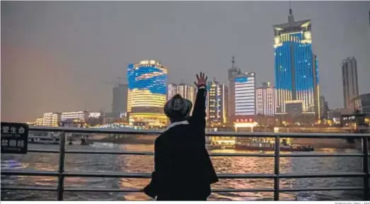  ?? ROMAN PILIPEY / EFE ?? Un hombre hace un saludo a la ciudad desde el ferry que cruza el río Yangtsé.