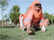  ?? — AFP ?? A female Afghan municipali­ty employee, supported by United Nations agency Un-habitat, removes weeds at a garden in Jalalabad.