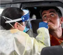  ?? —AFP ?? Precaution­s in motion: Medical staff taking samples from people at a drive-through testing site at a shopping centre car park in Melbourne.