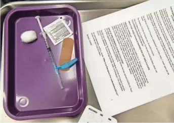  ?? MEG POTTER/THE REPUBLIC ?? A dose of the COVID-19 vaccine lies on a tray as a recipient fills out a form at Mountain Park Health Center in Tempe on Tuesday.