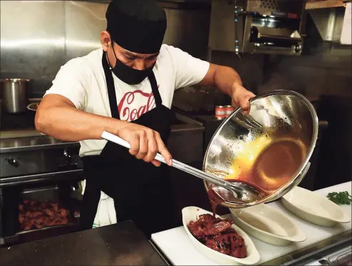  ?? Erik Trautmann / Hearst Connecticu­t Media ?? Cooks prepare menu items at Coals Grilled Pizza Tuesday in Norwalk. Coals Grilled Pizza, which has locations in Westcheste­r, opened their new location on Wall Street last Friday. It's the group's first location in Fairfield County/Connecticu­t and replaces Fat Cat Pizzeria which closed on Wall Street last year.