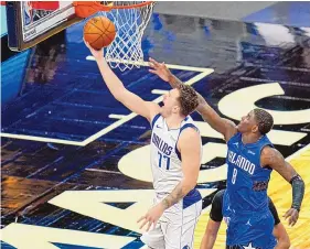  ?? JOHN RAOUX/ASSOCIATED PRESS ?? Luka Doncic of the Mavericks scores over Orlando’s Dwayne Bacon in second half of their game Monday night in Florida. Doncic had 33 points in Dallas’ victory.